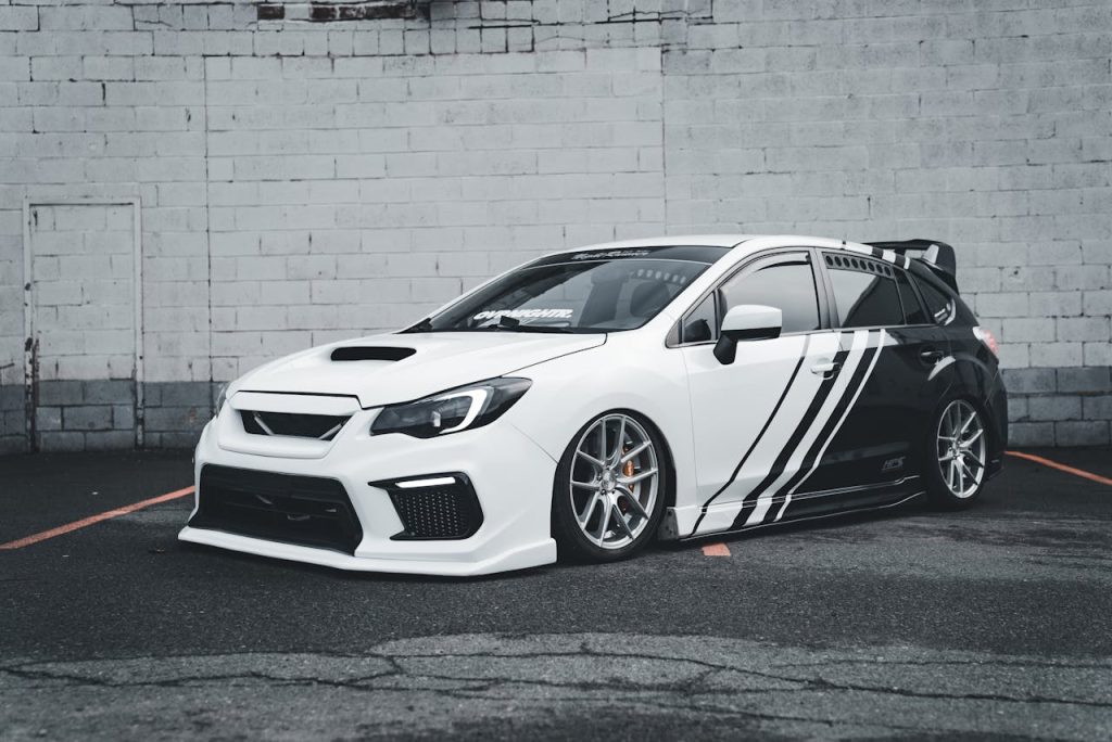 Stylish white sports car parked against a concrete wall in an urban environment.